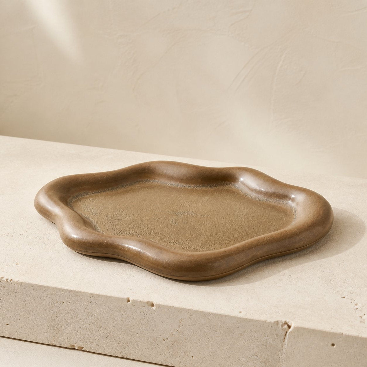 Bronze-brown cloud-shaped ceramic catchall tray viewed from a low side angle.