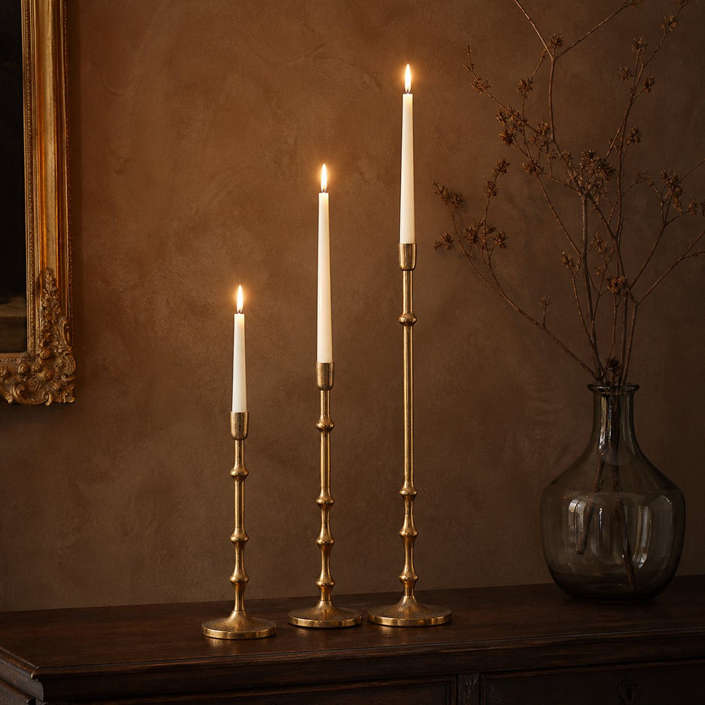 Hammered Brass-Tone Candlestick, lit taper candles on dark wood sideboard with gilt mirror