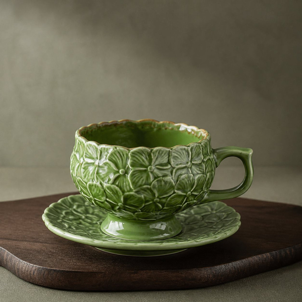 Sage Garden green ceramic cup and saucer with raised hydrangea floral relief on a walnut stand.