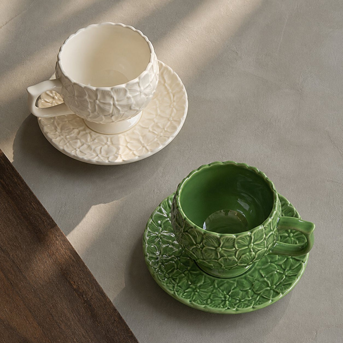 Overhead view of Ivory Bloom and Sage Garden hydrangea relief cup and saucer sets.