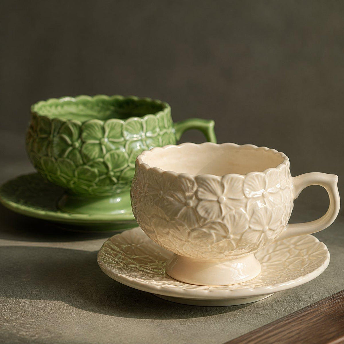 Close view of ivory and sage green ceramic cups with raised hydrangea petals.