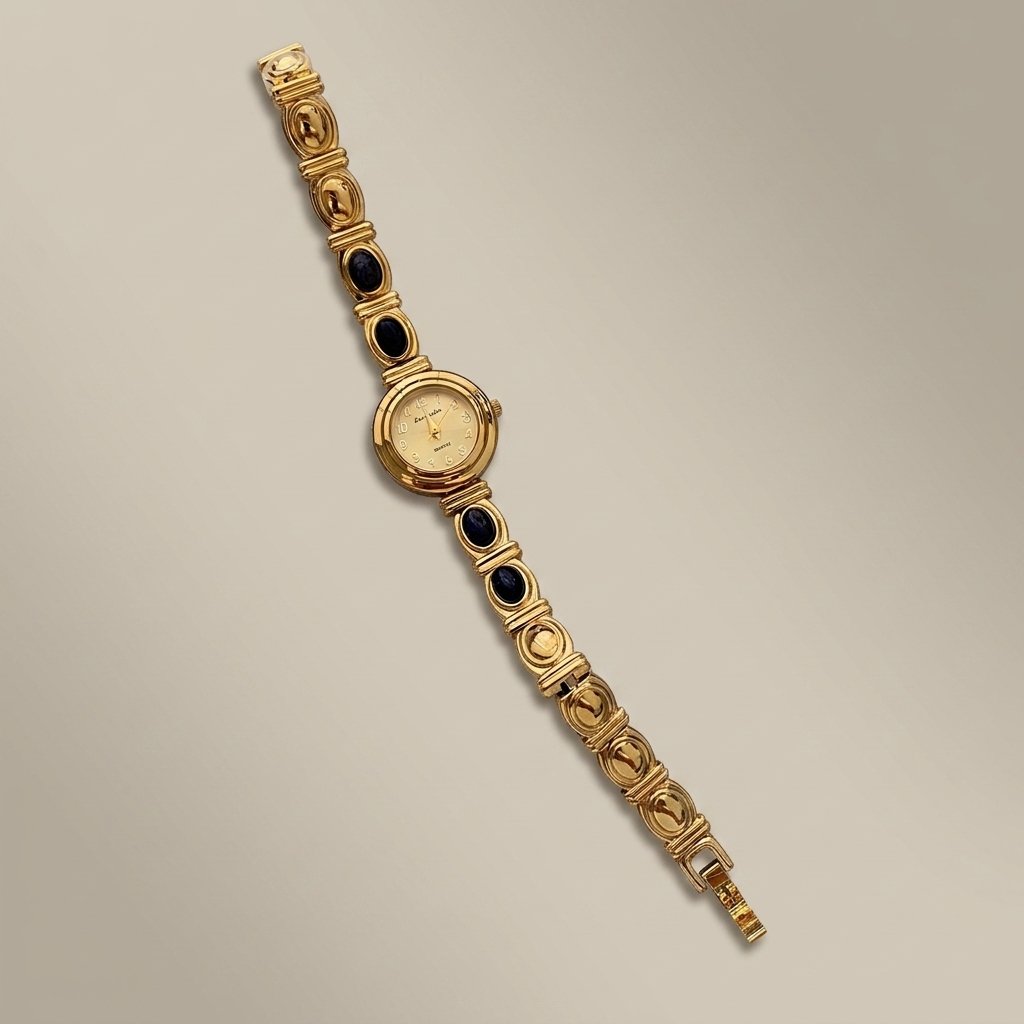 A vintage gold-tone watch with a multi-link bracelet featuring dark oval inlays and a round dial, displayed diagonally on a neutral beige background.
