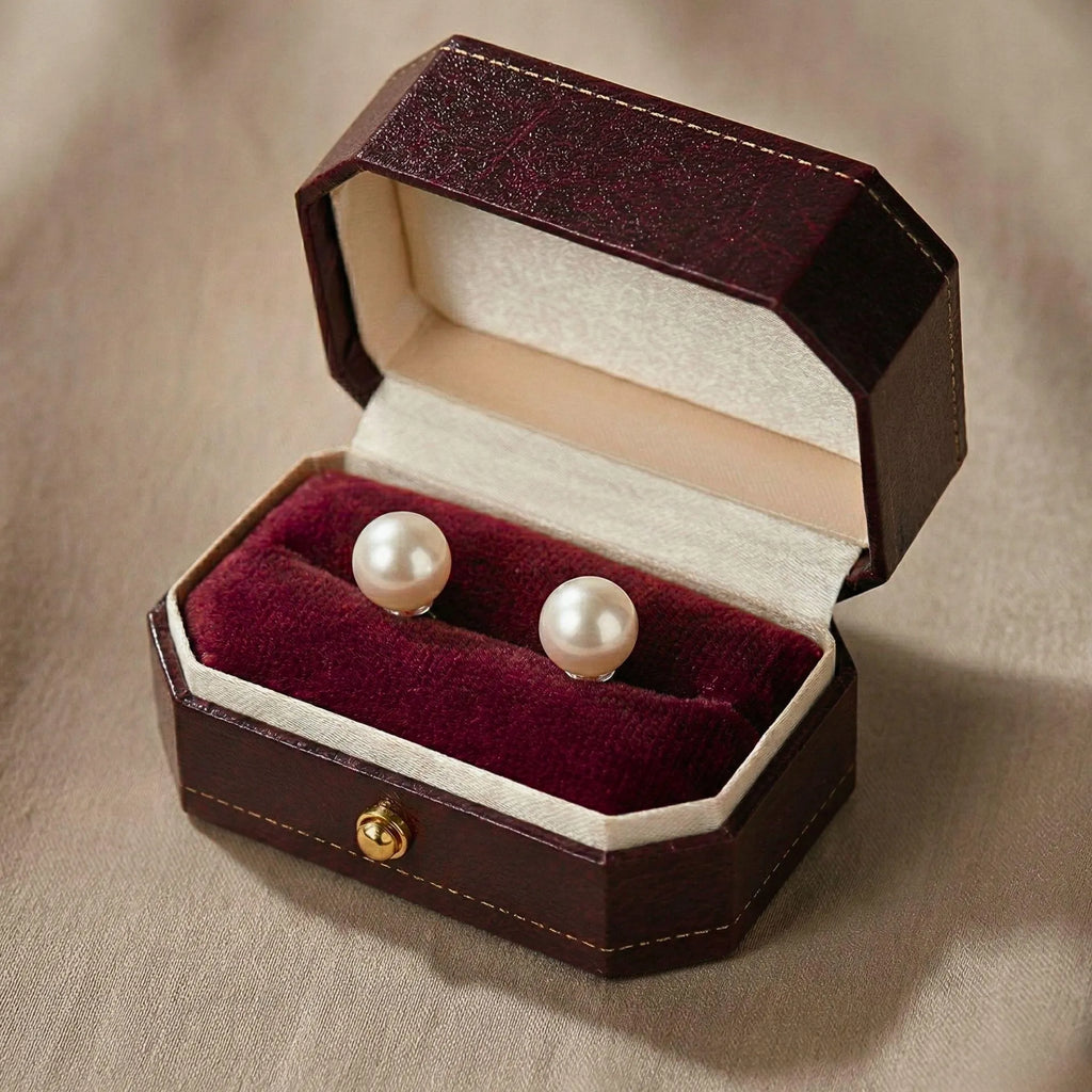 Two ring boxes side by side, one closed and one open holding a ring with pearl and gemstone accents