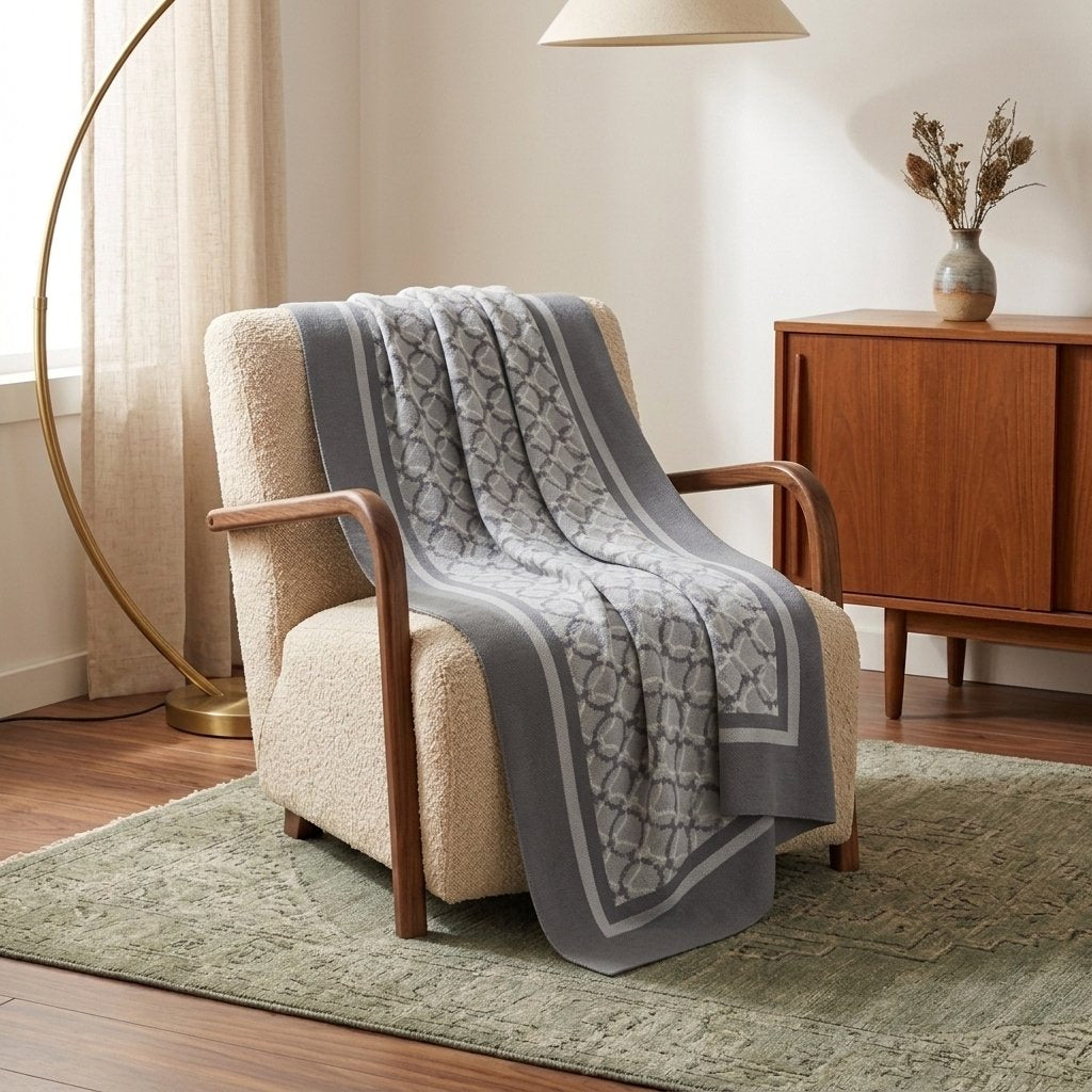 Light gray geometric knit throw blanket draped over a cream bouclé armchair in a sunlit retro living room