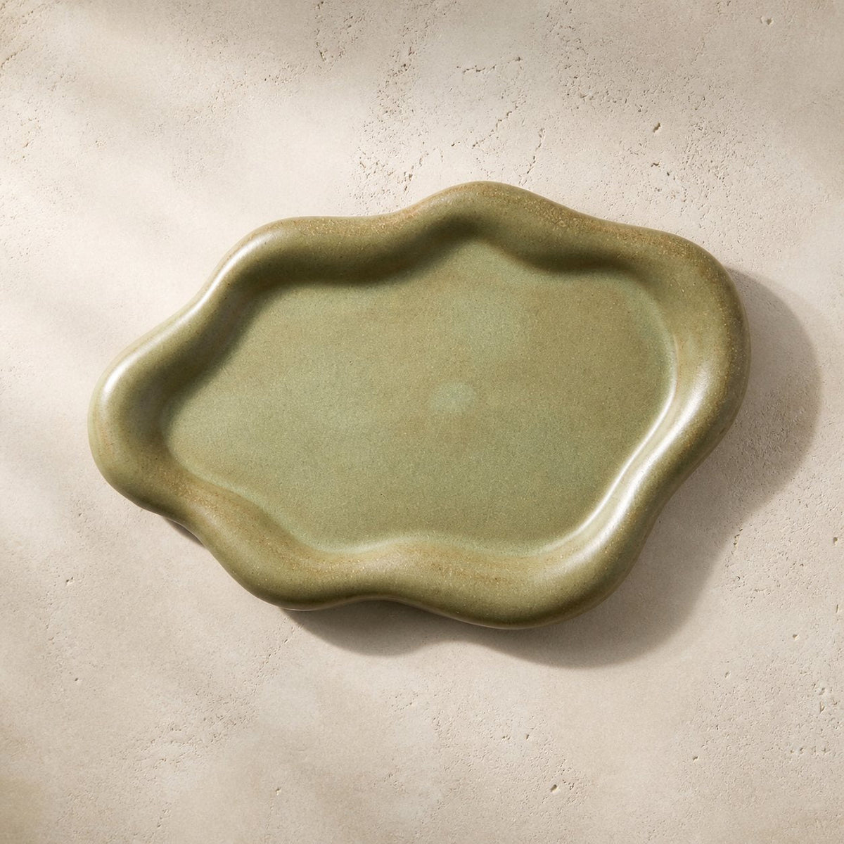 Olive green cloud-shaped ceramic catchall tray photographed from above.