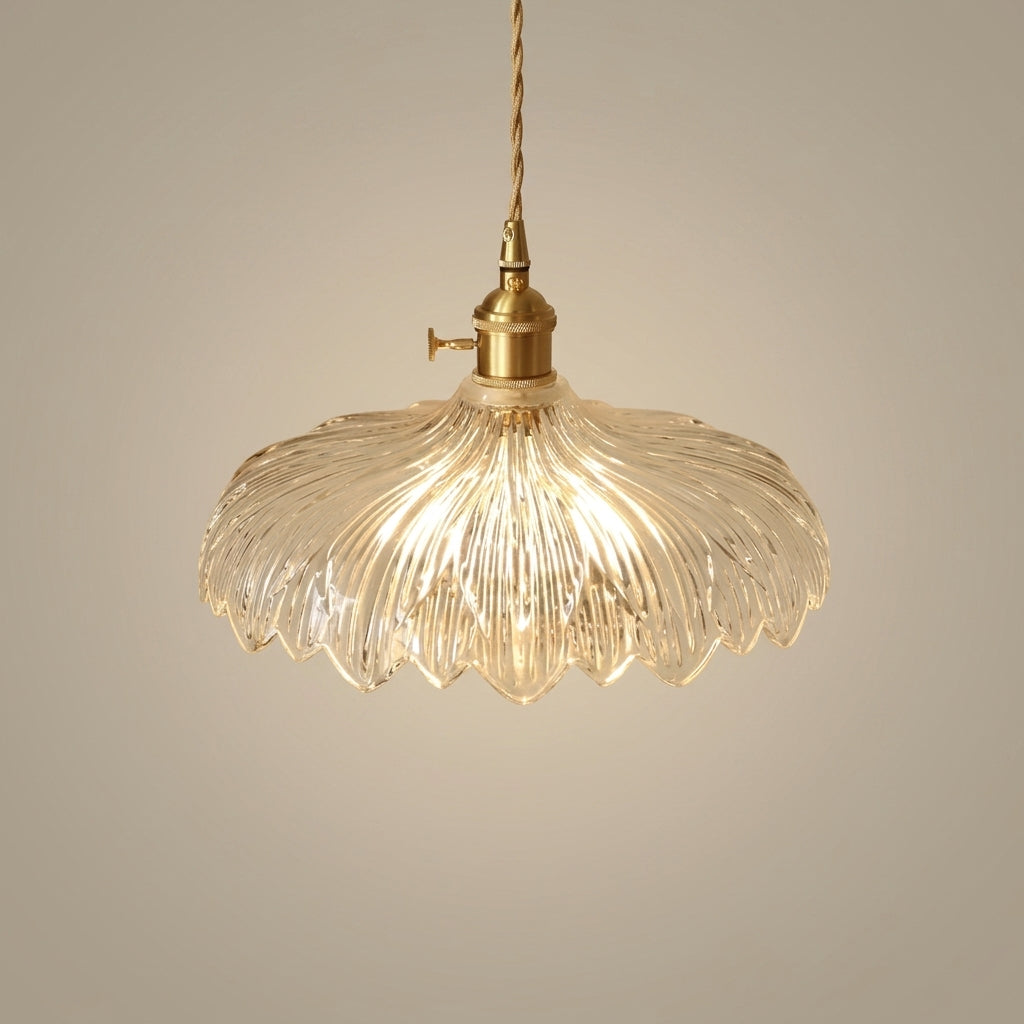 Clear ribbed glass pendant light with a scalloped edge and brass hardware, hanging against a neutral studio background
