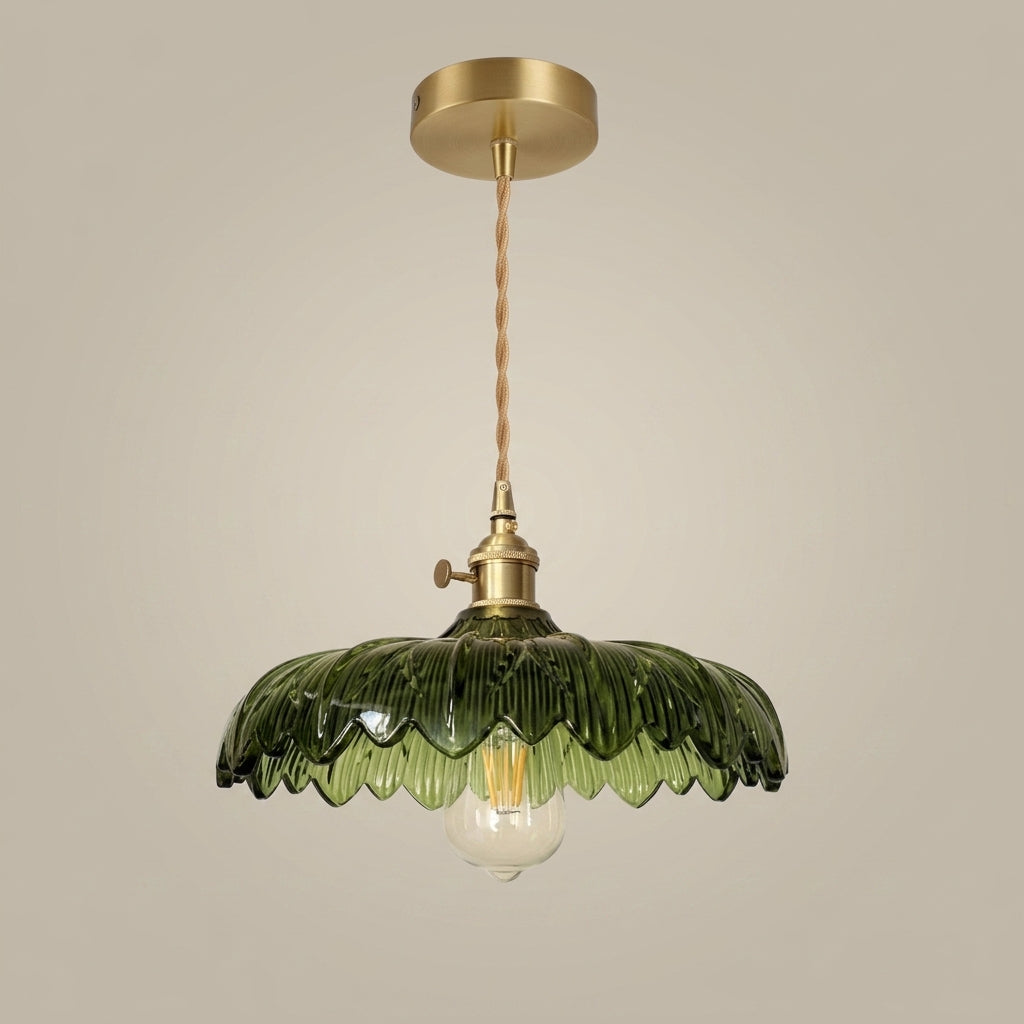 Emerald green ribbed glass pendant light with a scalloped edge and brass hardware, hanging against a neutral studio background