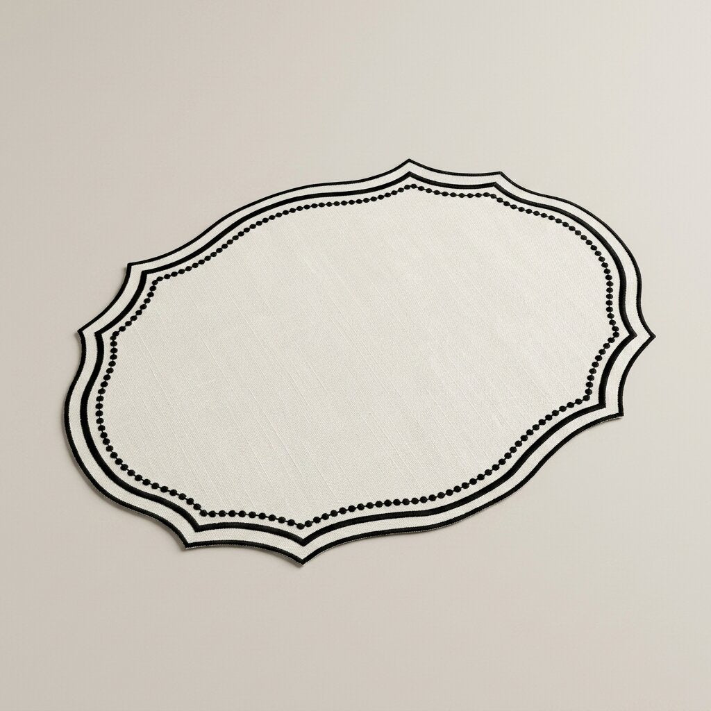 Oval placemat in ivory linen-look fabric with a black embroidered wavy edge, product photo